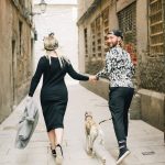 a couple holding each others hand while running with a dog