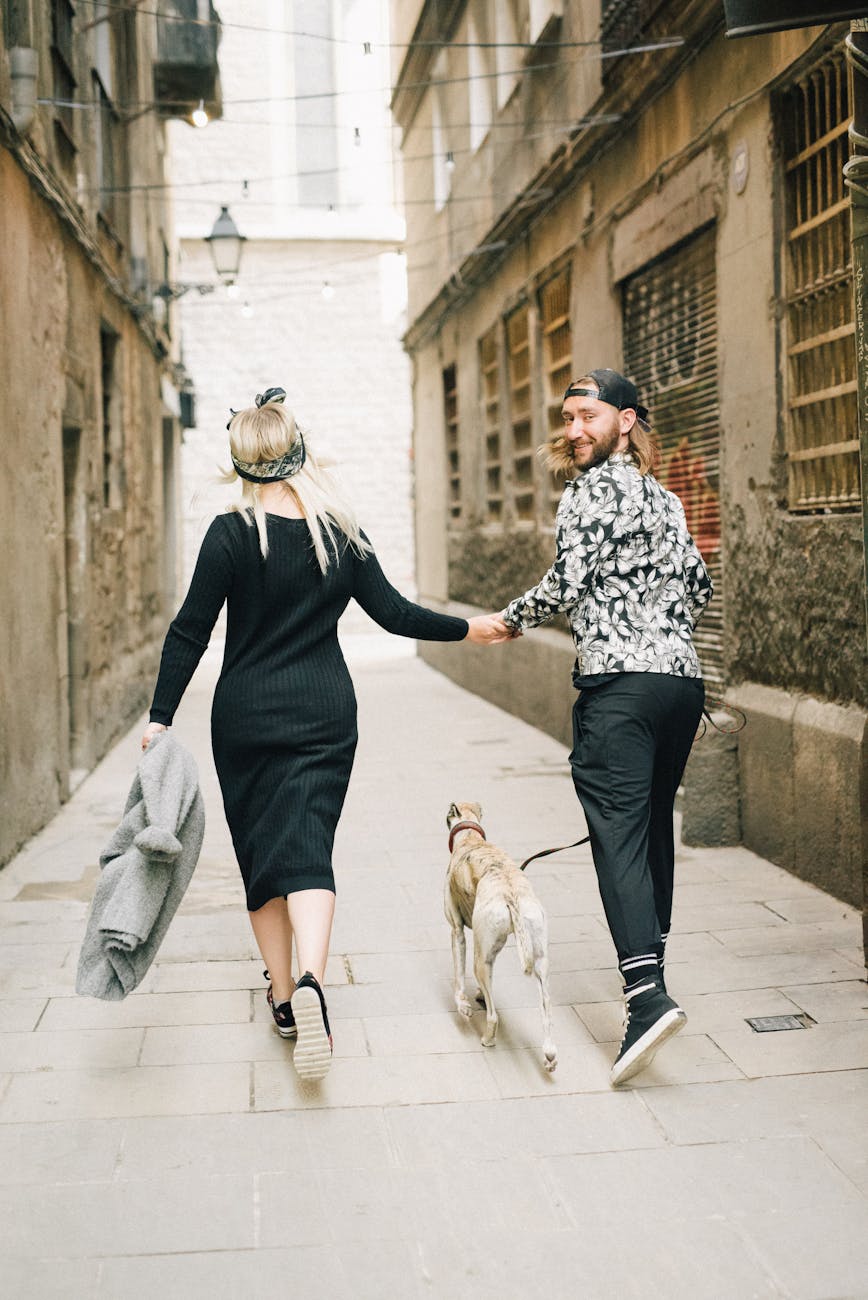 a couple holding each others hand while running with a dog